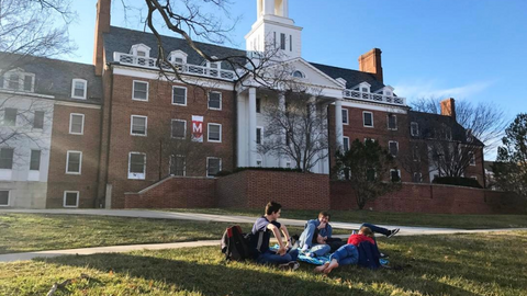 Students lounge in grass in front of Arundel Hall. 